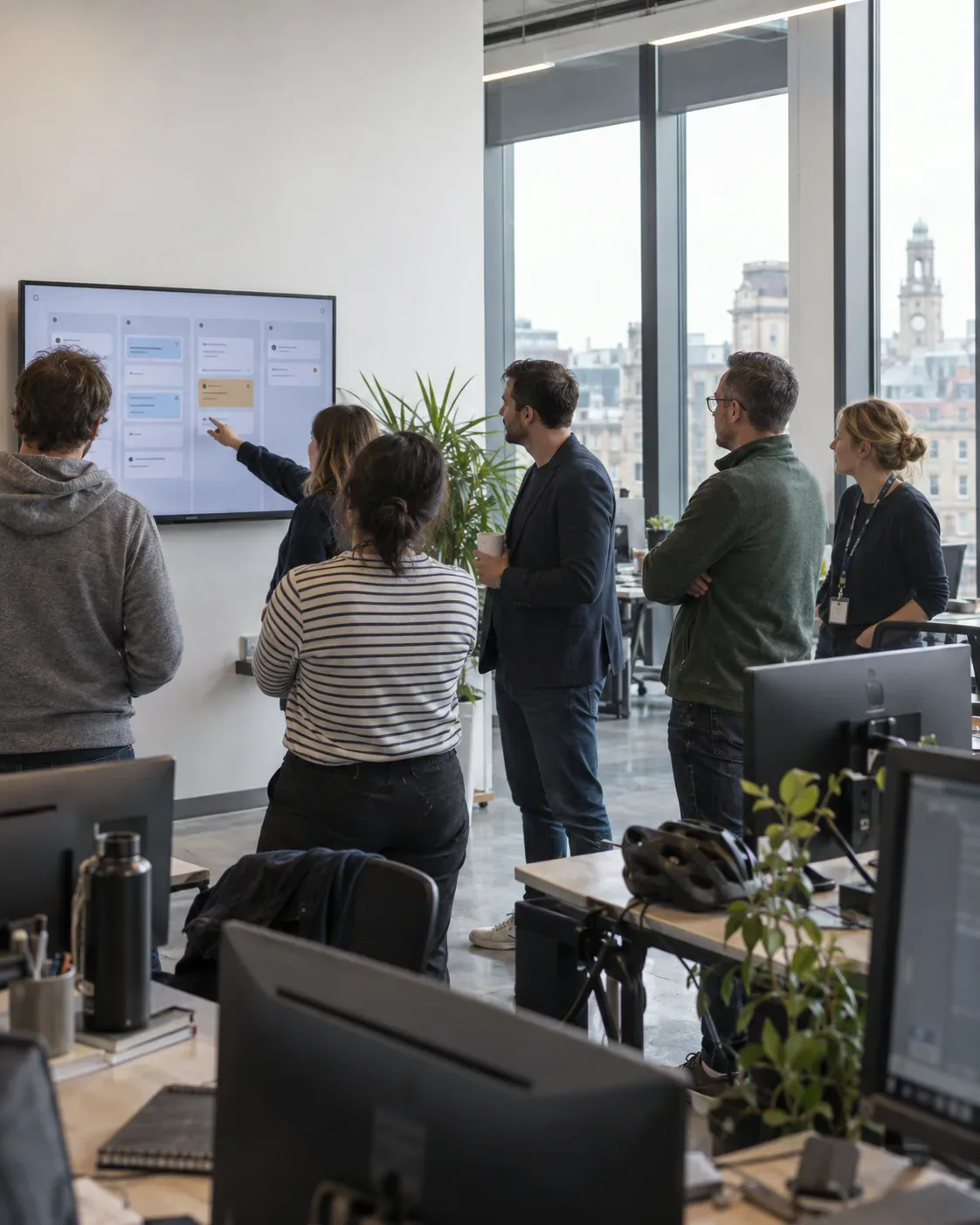 Team standing in front of a kanban board on a wall screen